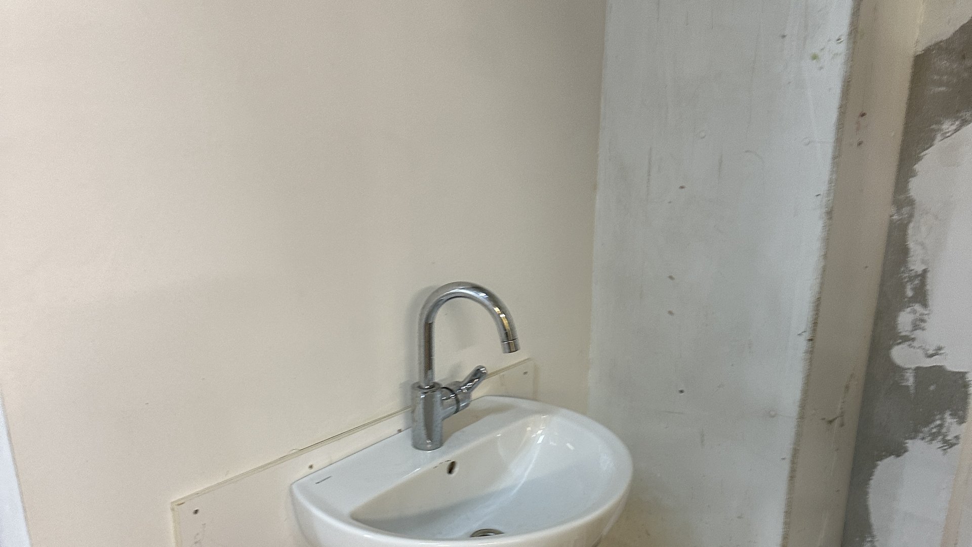 Fontein met kraan gemonteerd in nieuwbouw ruimte met zichtbare afvoerleidingen