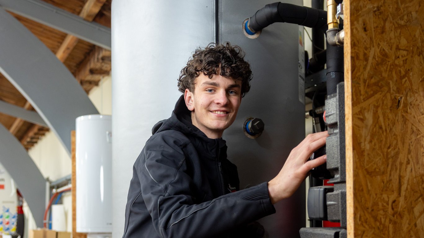 Monteur installatie werkzaamheden aan warmtepomp en boiler in technische ruimte