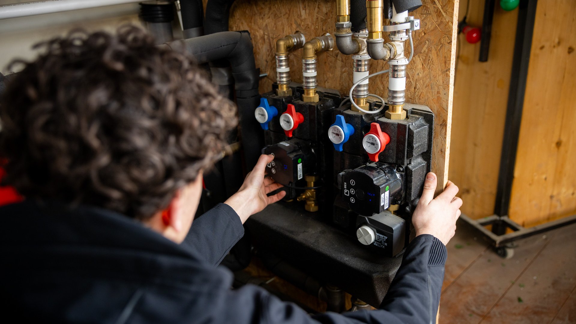 Monteur installeert hydraulisch verdeelstation met circulatiepompen