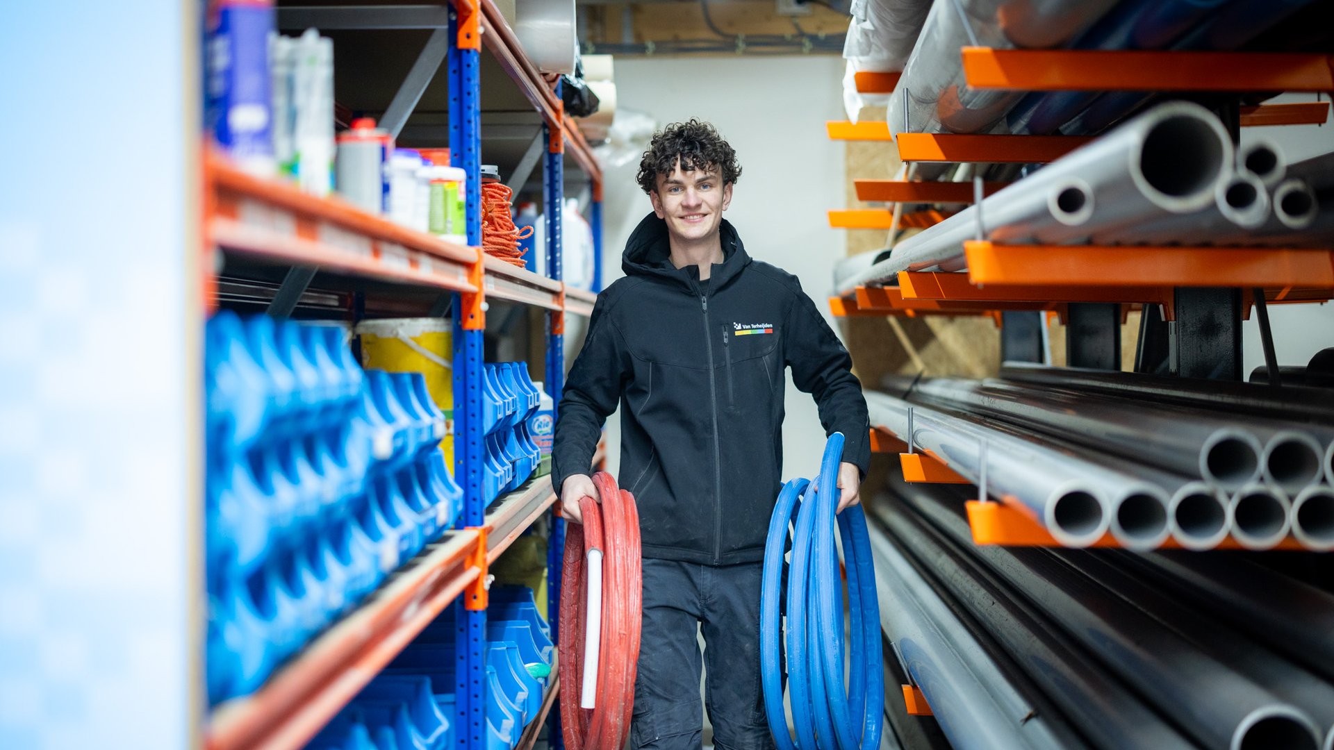 Monteur loopt door magazijn met leidingmateriaal