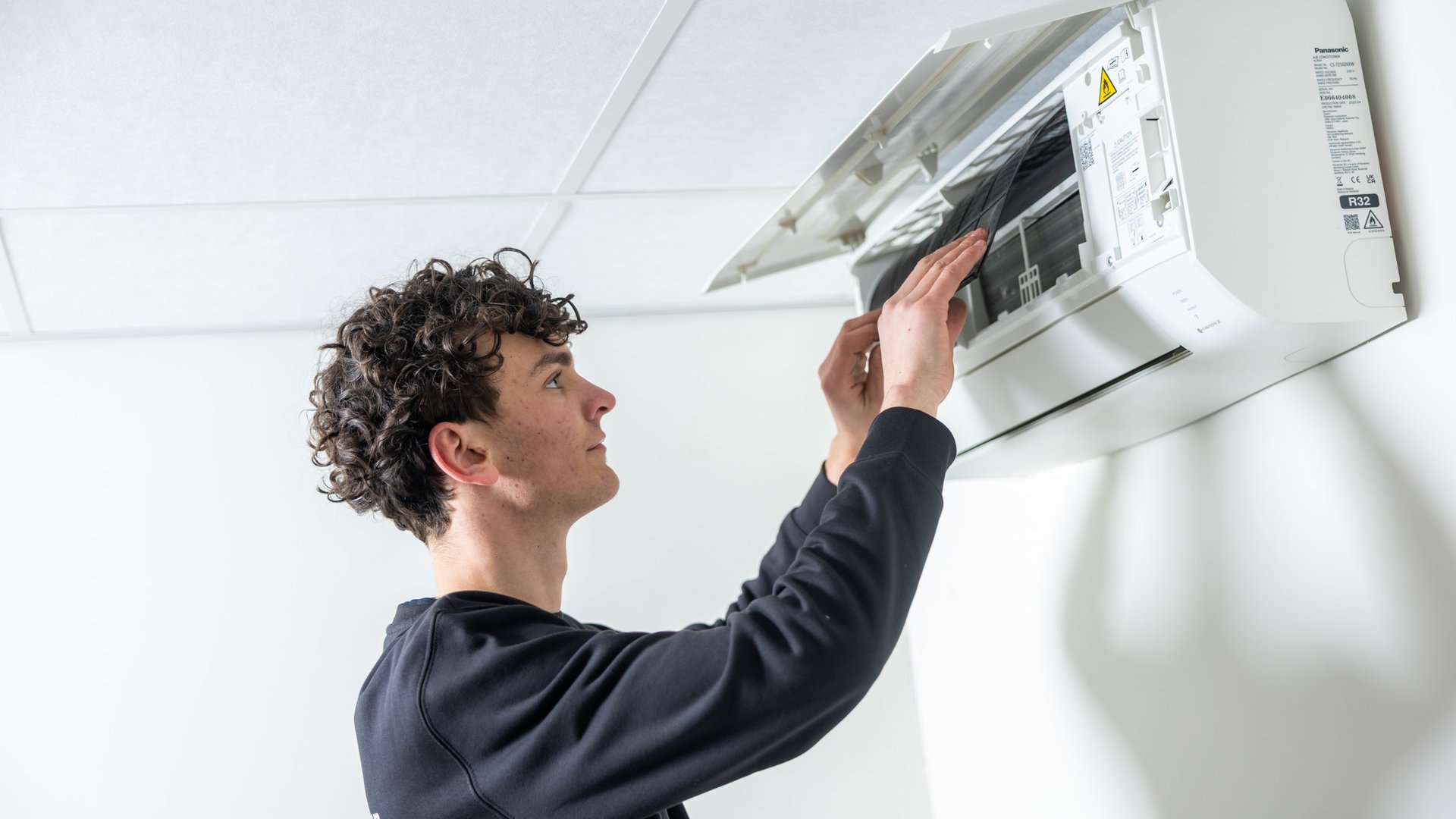 Monteur opent voorpaneel van Panasonic airco binnenunit