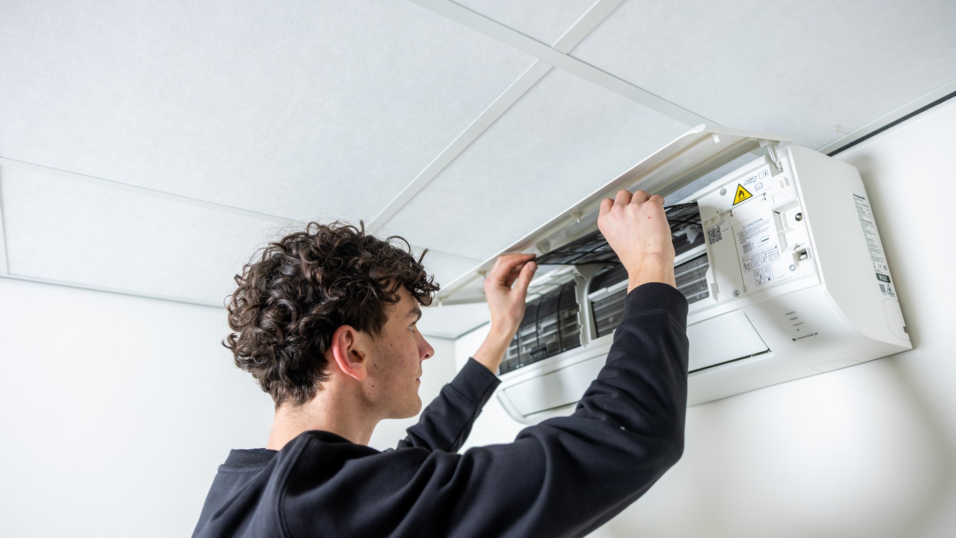 Monteur inspecteert binnenkant van airco binnenunit