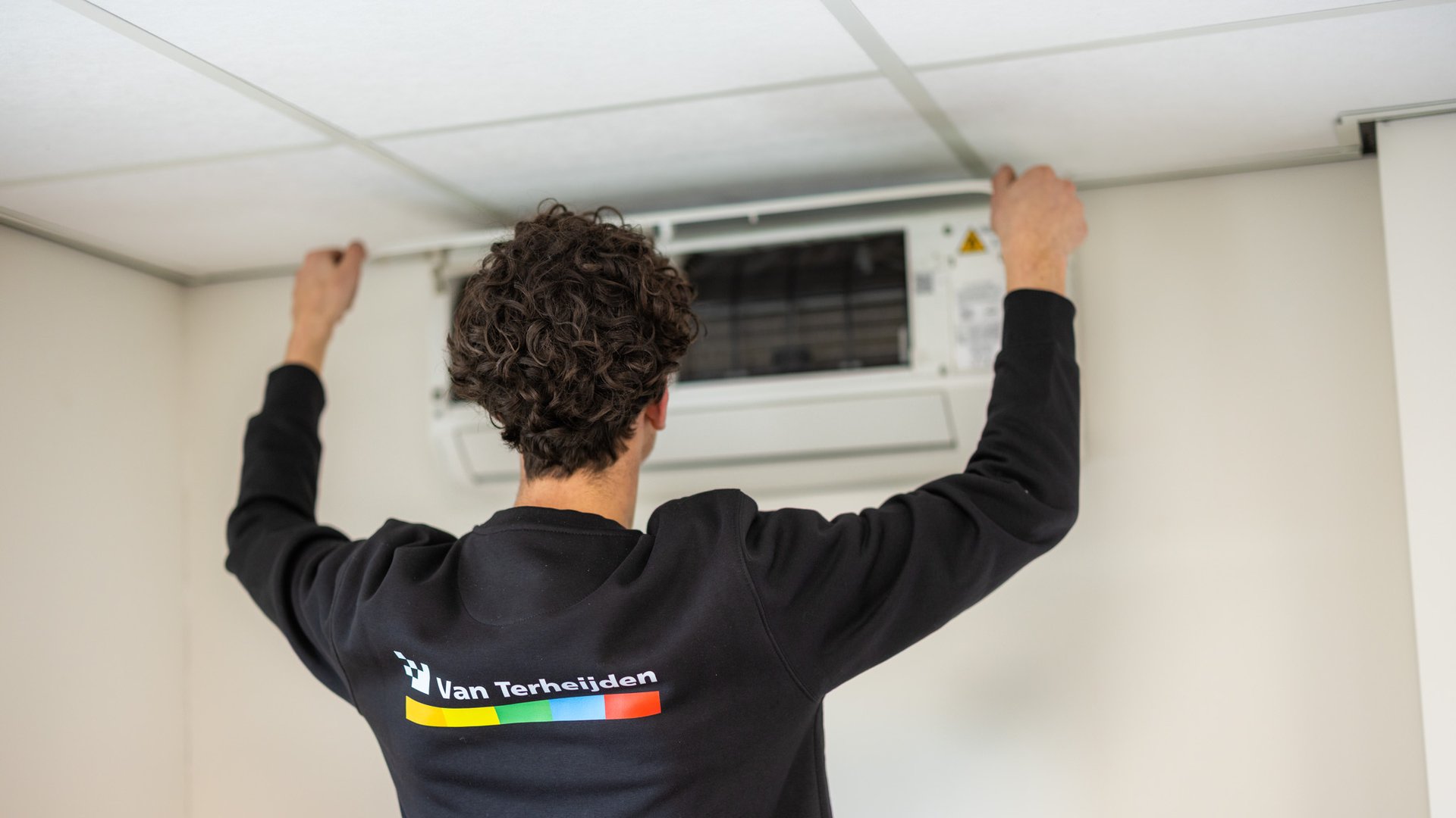 Monteur installeert airco-binnenunit aan het plafond