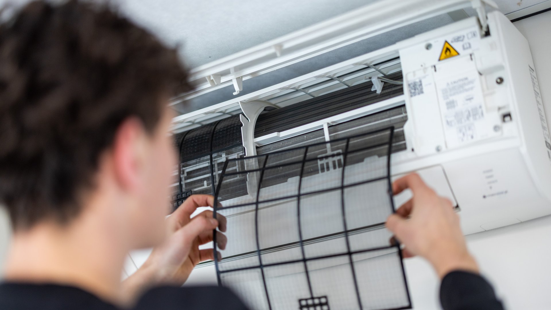 Monteur reinigt filter van airco-binnenunit